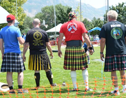 Highland Games four guys lined up wearing kilts