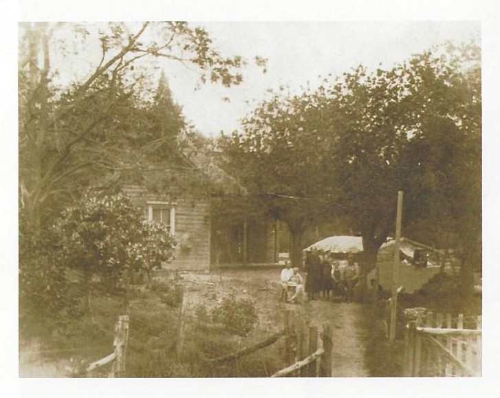 A black and white image of a family standing in front of a house