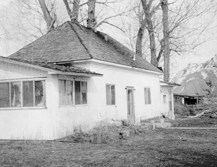 A black and white image of a house near trees